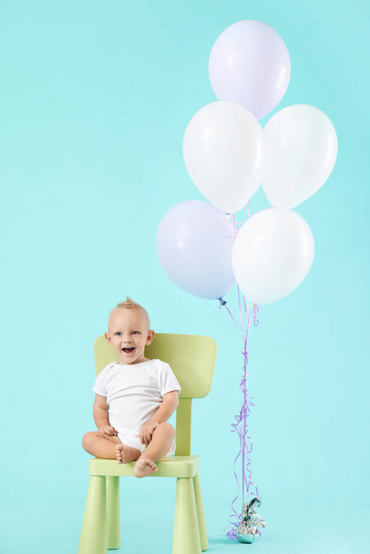 Portrait of cute little baby with air balloons on color background - Фото, зображення