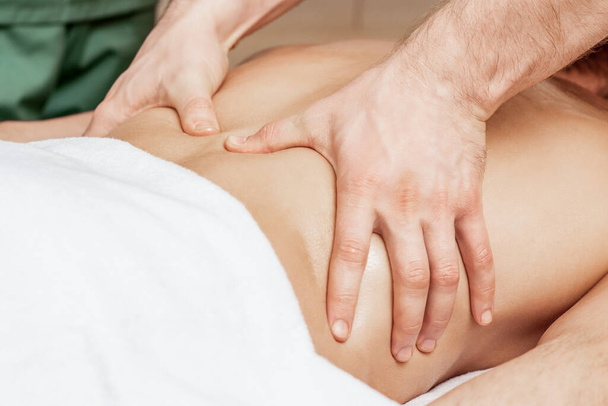 Massagetherapeut handen op rug tijdens rugmassage, close-up. - Foto, afbeelding