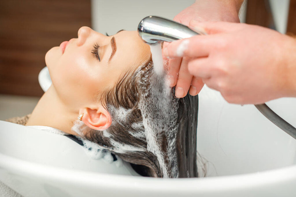 美容室でシンクで女性の髪を洗う美容師の手の閉じる - 写真・画像