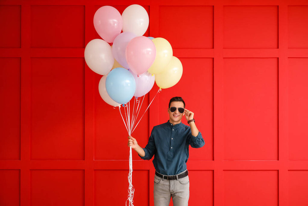 Young man with balloons on color background - Photo, image