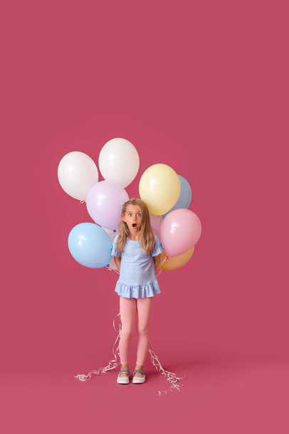 Zaskoczona dziewczynka z balonami na tle koloru - Zdjęcie, obraz