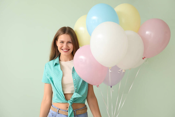 Young woman with balloons on color background - Fotoğraf, Görsel