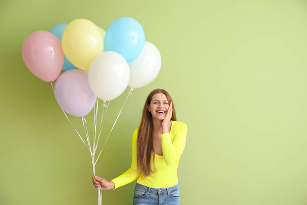 jonge vrouw met ballonnen op kleur achtergrond - Foto, afbeelding