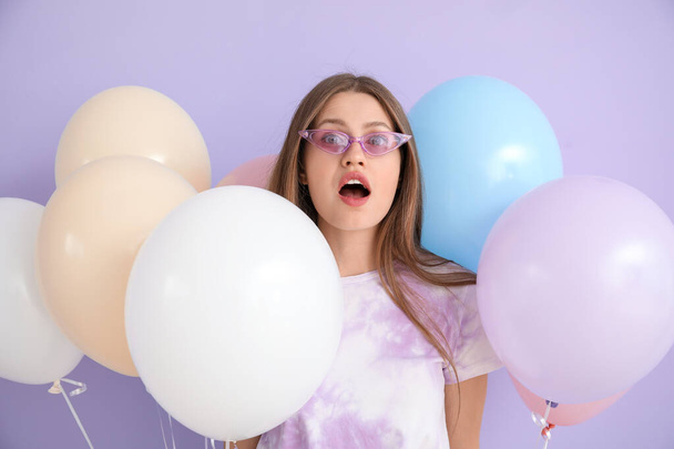 Mujer joven sorprendida con globos sobre fondo de color - Foto, Imagen