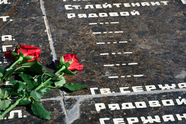 Russische Phrase "Sergeant, Major, Oberst, Leutnant, Ranker" - Dienstgrade der Armee, Blumen am Denkmal für gefallene Soldaten, rote Nelken auf schwarzem Marmor - Foto, Bild