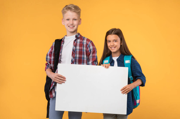 Podekscytowany dziewczyna i chłopiec trzyma biały pusty papier - Zdjęcie, obraz