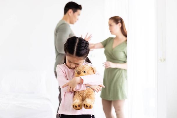 Asiatique petite fille enfant assis seul étreinte ours poupée émotion malheureux et tristesse parce que père et mère querelle. - Photo, image