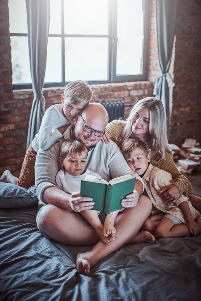 Niños felices y sus padres leyendo cuentos de hadas en el hotel - Foto, imagen