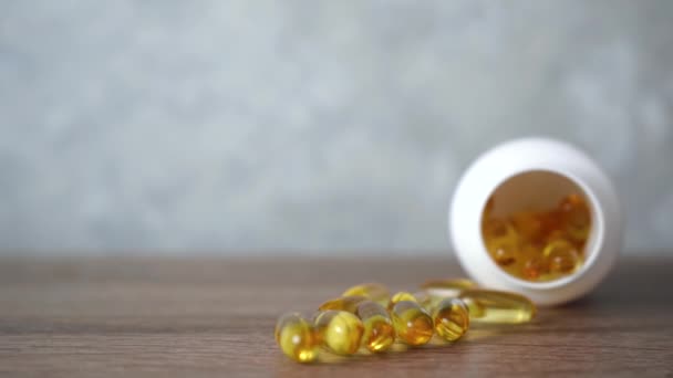 A halolaj tabletták egy fából készült asztalon vannak. Világos sárga fényes Omega 3 tabletta. - Felvétel, videó