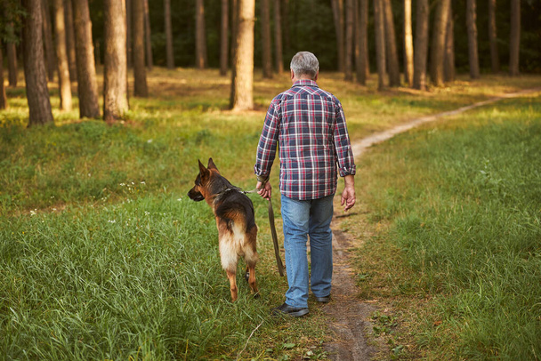Пожилой человек гуляет со своей собакой - Фото, изображение