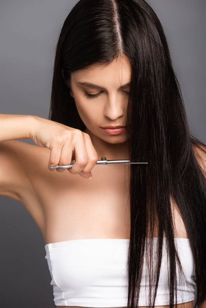 brunette woman cutting hair isolated on black - Photo, Image