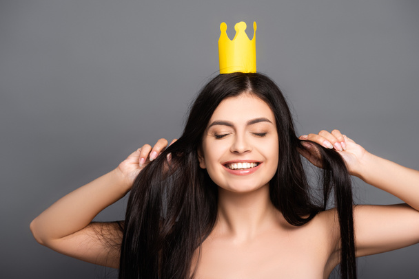 naked brunette long haired woman in crown smiling isolated on black - 写真・画像