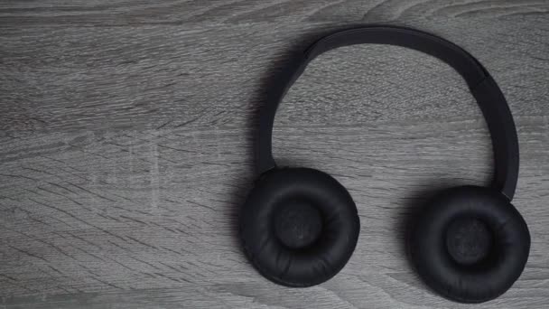 auriculares negros se encuentran sobre un fondo de madera - Metraje, vídeo