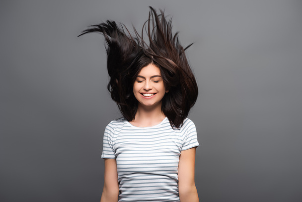 brunetka dlouhé vlasy žena skákání a usmívání izolované na černé - Fotografie, Obrázek