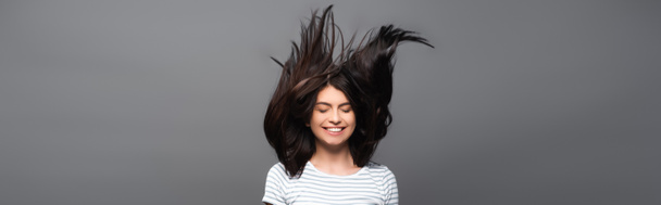brunette long haired woman jumping and smiling isolated on black, panoramic shot - 写真・画像