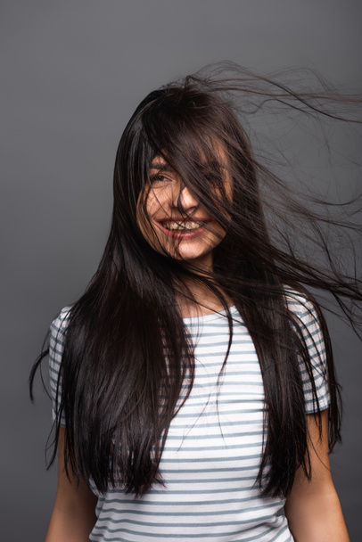 wind blowing through hair of brunette woman isolated on black - Foto, afbeelding