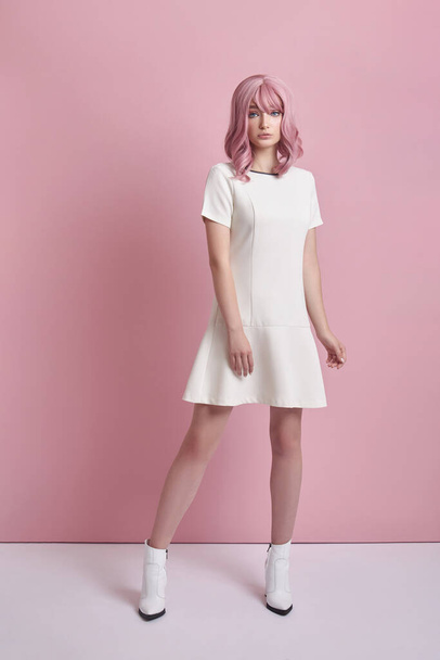 Beautiful girl with pink hair, hair coloring. Cute anime woman stands on a pink background in a short white dress. Colored hair, perfect hairstyle - Φωτογραφία, εικόνα