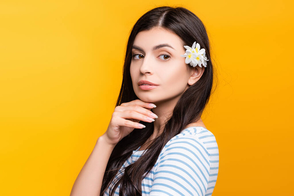 brunette young woman with flowers in hair looking away isolated on yellow - Photo, Image