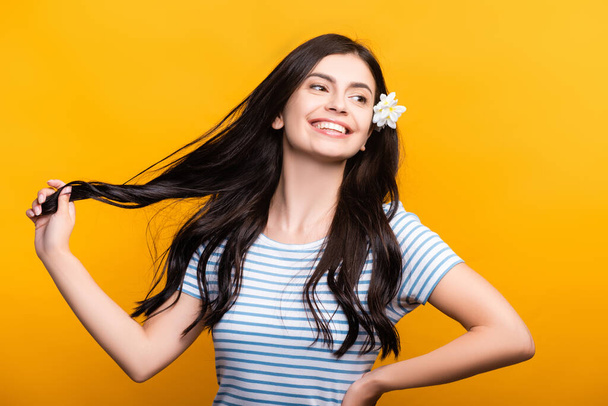 brunette young woman with flowers in hair smiling isolated on yellow - Fotografie, Obrázek