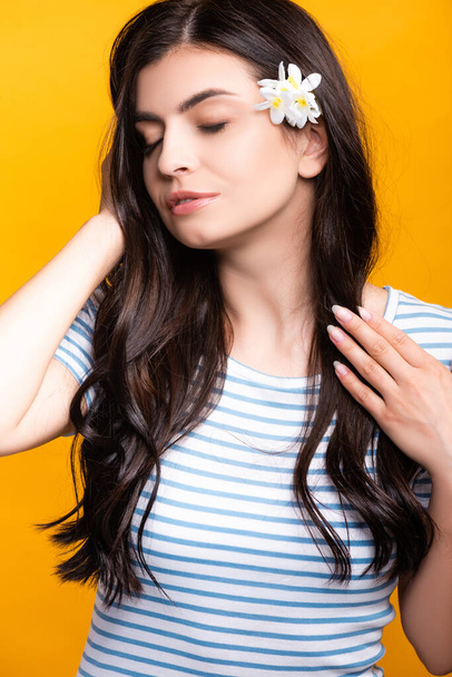 brunette young woman with flowers in hair and closed eyes isolated on yellow - Foto, Imagem