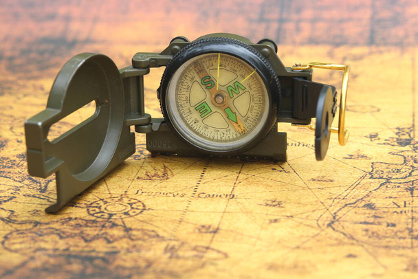 Klasický kruhový kompas na pozadí staré retro mapy světa jako symbol cestovního ruchu s kompasem, cestování s kompasem a outdoorových aktivit s kompasem - Fotografie, Obrázek