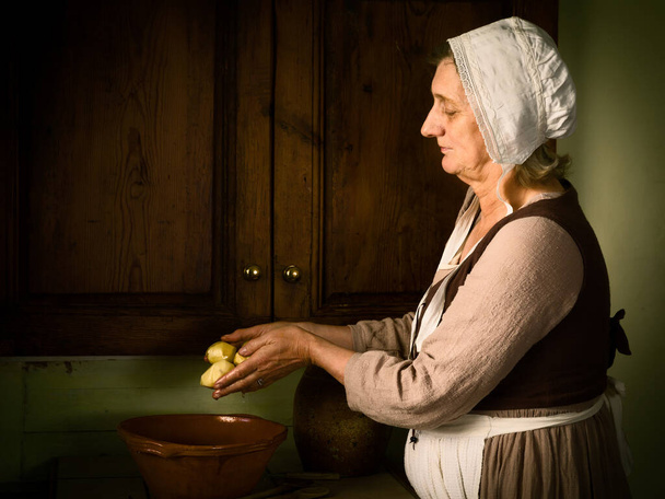 Old Master style Renaissance portrait of a woman preparing food in an antique kitchen - Fotografie, Obrázek