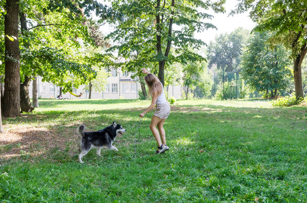 houkutteleva blondi kulkee ja leikkii koiransa kanssa puistossa. - Valokuva, kuva