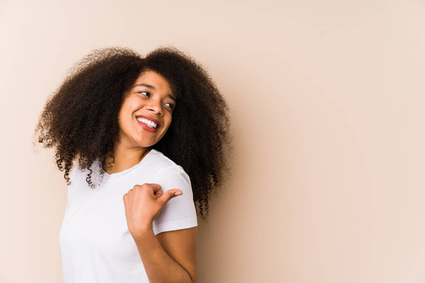 Genç Afrikalı Amerikalı kadın başparmağıyla işaret ediyor, gülüyor ve kaygısız.. - Fotoğraf, Görsel
