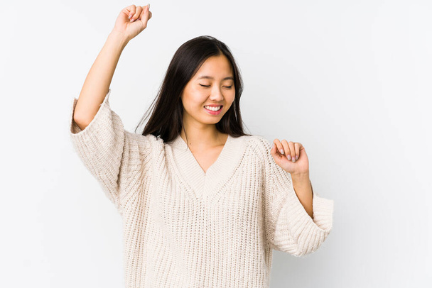 Νεαρή Κινέζα γυναίκα απομονωμένη γιορτάζει μια ξεχωριστή μέρα, πηδάει και σηκώνει τα χέρια με ενέργεια. - Φωτογραφία, εικόνα