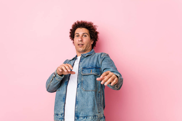 Curly mature man wearing a denim jacket against pink background being shocked due to an imminent danger - Valokuva, kuva