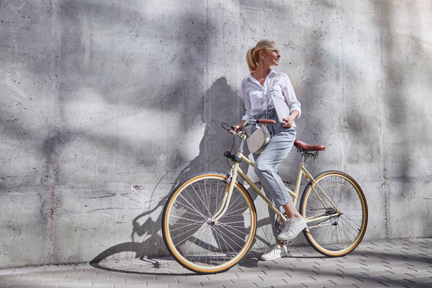 Elegante dama de buen aspecto con bicicleta retro disfrutando de un buen clima cálido de otoño en la ciudad - Foto, imagen