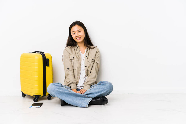 Молодая китайская путешественница сидящая с посадочными талонами счастливая, улыбающаяся и веселая. - Фото, изображение