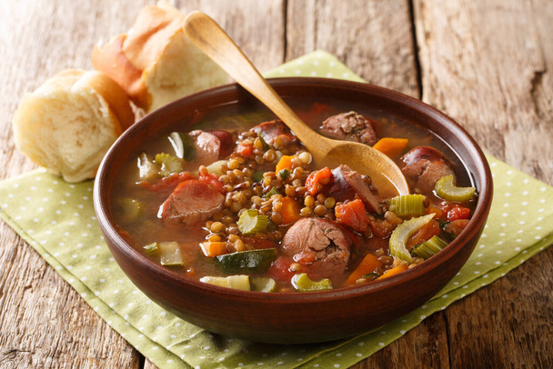 Ароматический здоровый чечевичный суп с сезонными овощами и копченой колбасой крупным планом в тарелке на столе. hhhonta - Фото, изображение