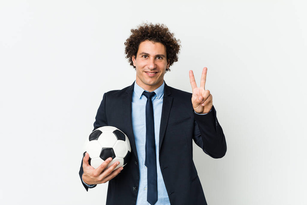 Trener piłki nożnej trzyma piłkę pokazując numer dwa palcami. - Zdjęcie, obraz