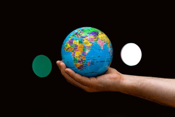 Planeta Globe Země v ruce člověka proti barevným lampám se rozmazala. Koncept podnikání, politiky, ekologie a médií. Pozemní noc abstraktní pozadí. - Fotografie, Obrázek