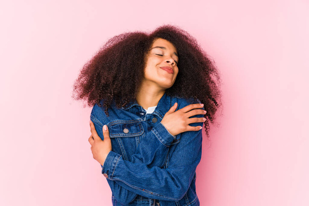 Νεαρή Αφροαμερικάνα αγκαλιάζει, χαμογελώντας ανέμελη και ευτυχισμένη. - Φωτογραφία, εικόνα