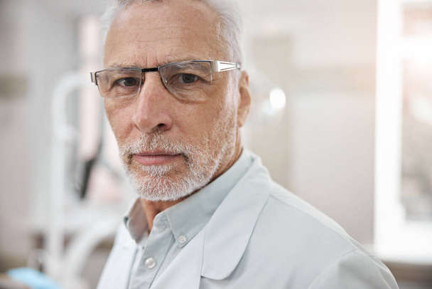 Determined dentist in glasses posing in his office - Фото, зображення