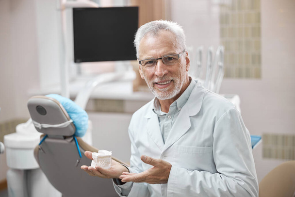 Professional dentist demonstrating a custom plaster mold of teeth - Fotoğraf, Görsel