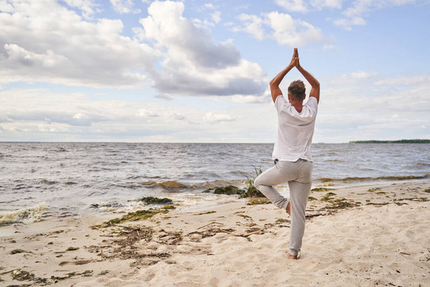 Mies harjoittelee joogaa yksinäisyydessä rannalla - Valokuva, kuva