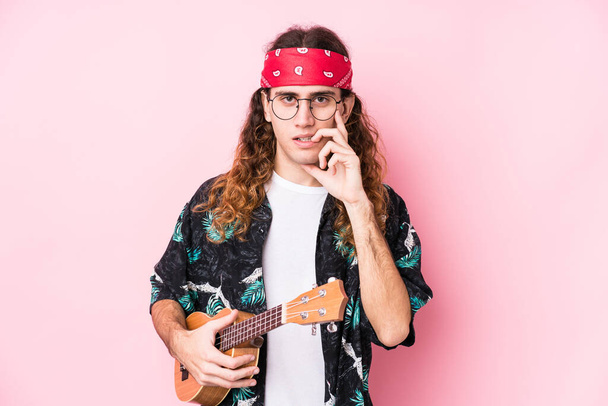 Long hair hippie man holding a ukelele isolated biting fingernails, nervous and very anxious. - Photo, Image
