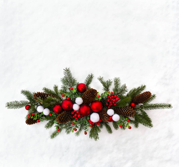 Świąteczne dekoracje. Gałązki choinki, bożonarodzeniowe kulki, szyszki świerk i czerwone jagody na śniegu z miejscem na tekst. Widok z góry, płaski - Zdjęcie, obraz