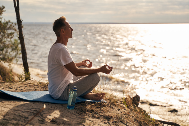 Calm mature man meditating on sea shore - Photo, Image