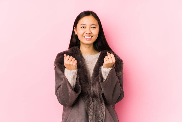 Joven mujer china usando un abrigo aislado animando despreocupado y emocionado. Concepto de victoria. - Foto, imagen