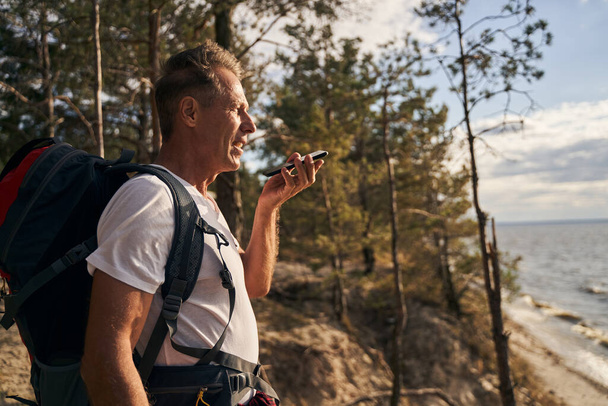 Happy male talking on cell phone while hiking - Photo, Image