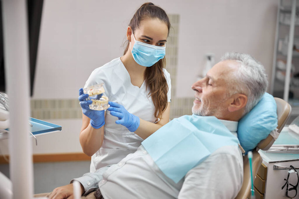 Кваліфікований жіночий стоматолог, який тримає зубні імплантати
 - Фото, зображення