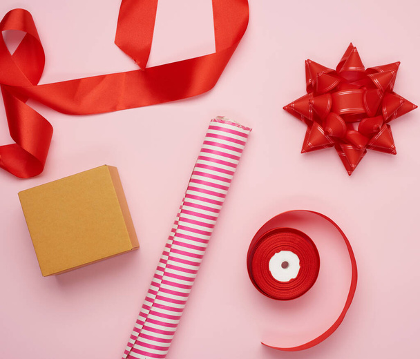 wrapping paper roll, box and red silk ribbon with bow, items for gift wrapping, top view - Φωτογραφία, εικόνα