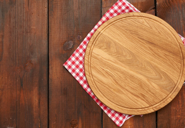 nueva tabla de cortar de madera redonda vacía en la mesa marrón, vista superior - Foto, imagen