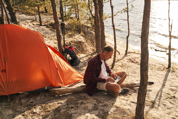 Serene mâle va camper avec ordinateur portable en bois - Photo, image