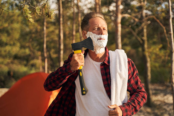 Homem engraçado usando machado para barbear na natureza - Foto, Imagem