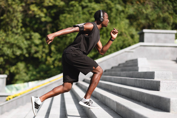 Estilo de vida activo. Deportivo negro corredor masculino corriendo en pasos en parque urbano - Foto, imagen